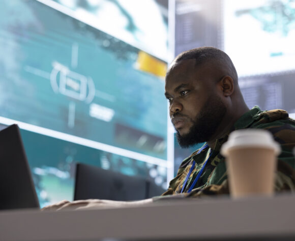Secret service expert in an advanced command post manages reconnaissance Secret service expert in an advanced command post manages reconnaissance and intelligence gathering activity, interprets real time data. IT analyst in base of operations with big screen.